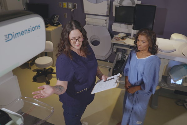 Radiologist shows a mammography system to a woman during a mammography exam